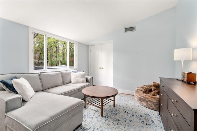 living area featuring vaulted ceiling and baseboards