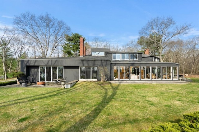 back of property featuring a chimney, a yard, and a patio