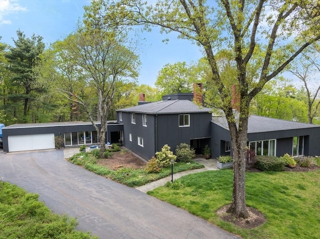 view of front facade with a chimney, a front yard, and a garage