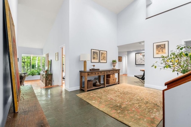 hallway featuring a towering ceiling and baseboards