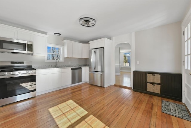 kitchen with white cabinetry, sink, stainless steel appliances, and light wood-type flooring