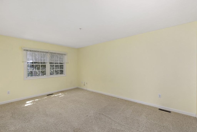 carpeted spare room featuring baseboards and visible vents