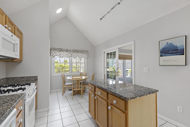 kitchen featuring dark stone countertops, vaulted ceiling, baseboards, and white appliances