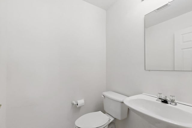 half bathroom with toilet, visible vents, and a sink