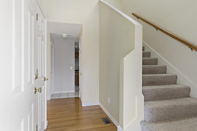 staircase with visible vents, wood finished floors, and baseboards