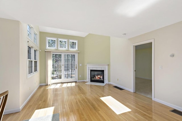 unfurnished living room with light wood-style floors, visible vents, a fireplace, and baseboards