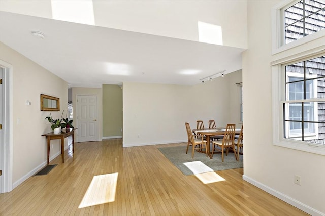 dining space featuring track lighting, light wood-type flooring, visible vents, and baseboards
