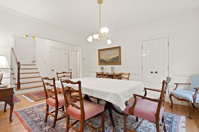 210 Melrose St, Newton, MA 02466 - dining room with ornamental molding, a chandelier, stairs, light wood-style floors, and arched walkways