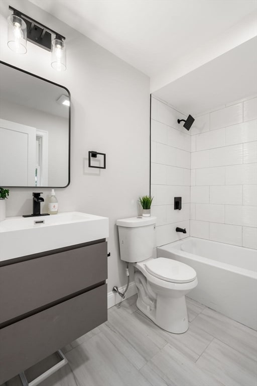 full bathroom featuring vanity, tiled shower / bath combo, and toilet