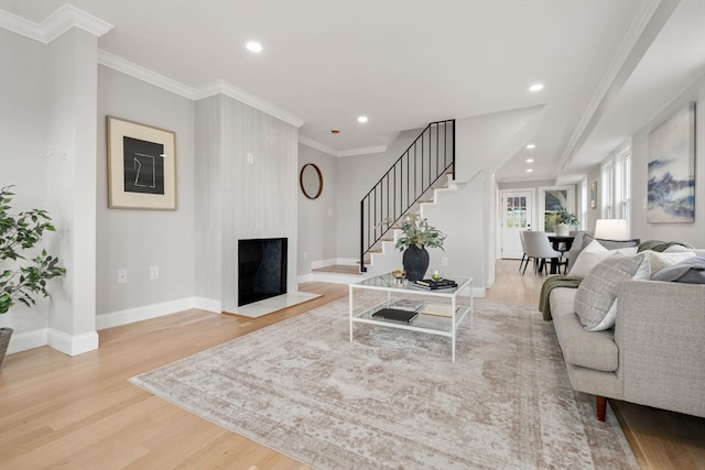 living room featuring a fireplace, light wood-type flooring, and ornamental molding