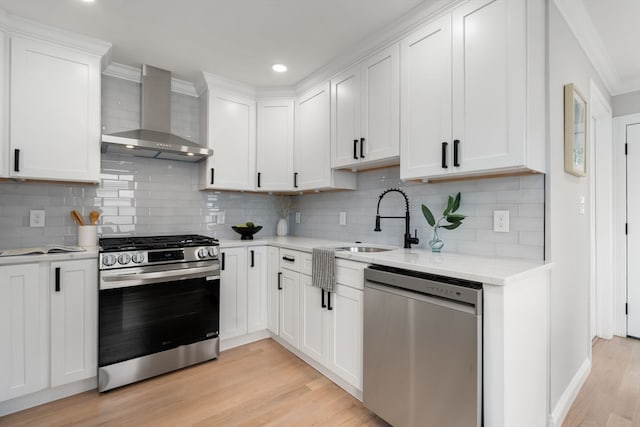 kitchen featuring white cabinetry, wall chimney range hood, stainless steel appliances, and tasteful backsplash