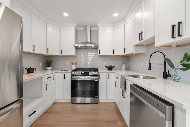 kitchen featuring white cabinets, wall chimney exhaust hood, light wood-type flooring, appliances with stainless steel finishes, and tasteful backsplash