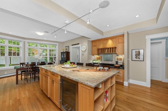 kitchen featuring beverage cooler, open shelves, light wood finished floors, and baseboards