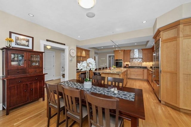 dining area featuring light wood-type flooring, a tray ceiling, and recessed lighting