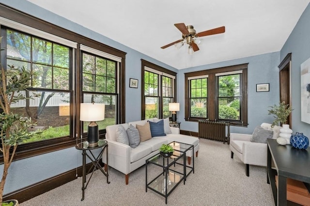 living area with radiator, healthy amount of natural light, ceiling fan, and baseboards