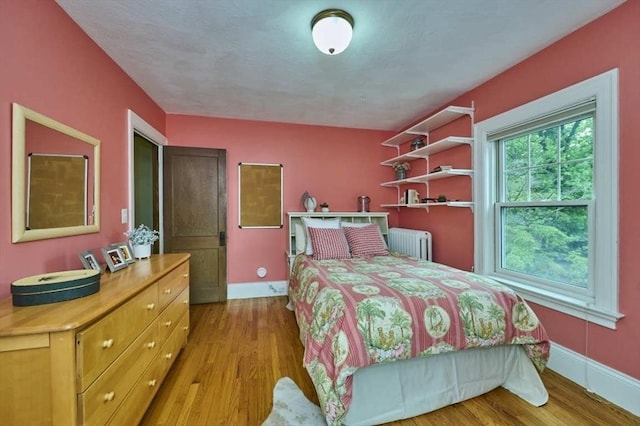 bedroom featuring radiator heating unit, wood finished floors, and baseboards