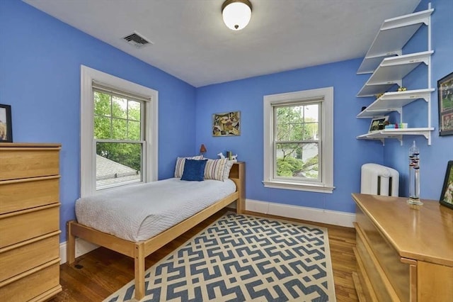 bedroom with radiator, wood finished floors, and baseboards