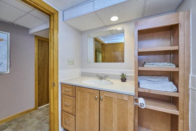 bathroom with a paneled ceiling, vanity, and baseboards