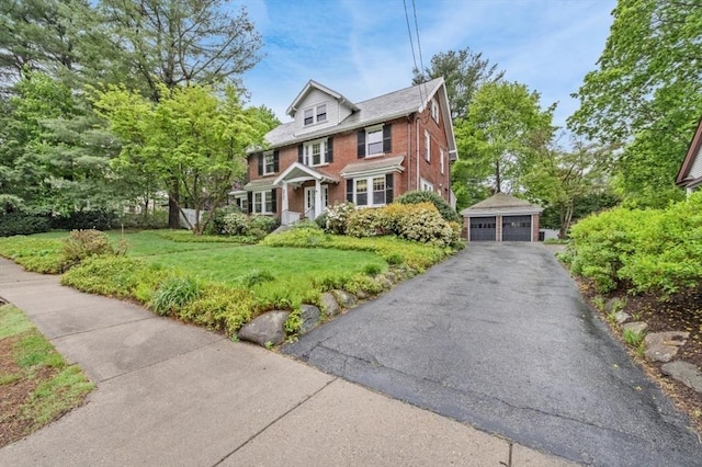 view of front of house featuring brick siding, a garage, an outbuilding, and a front yard