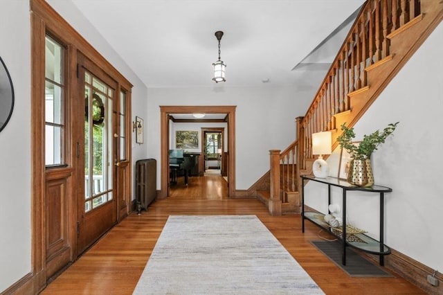 foyer entrance featuring radiator, stairs, light wood-style flooring, and baseboards