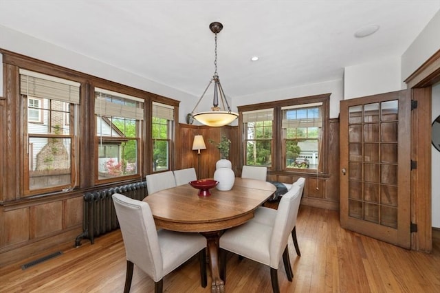 dining area featuring radiator and light wood finished floors