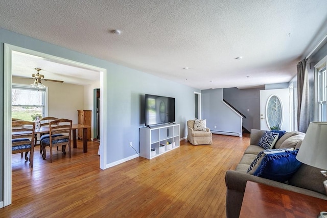 living room with stairway, baseboards, light wood-type flooring, and a textured ceiling