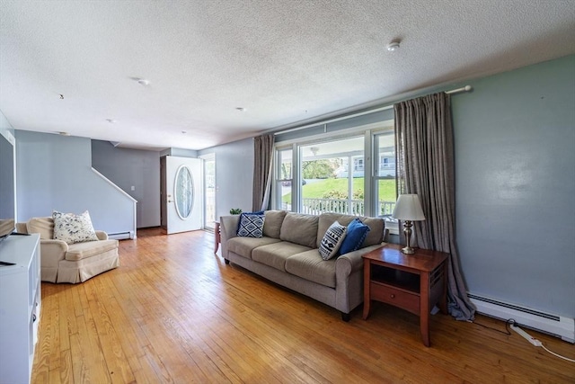 living area featuring light wood-style floors, baseboard heating, and a textured ceiling