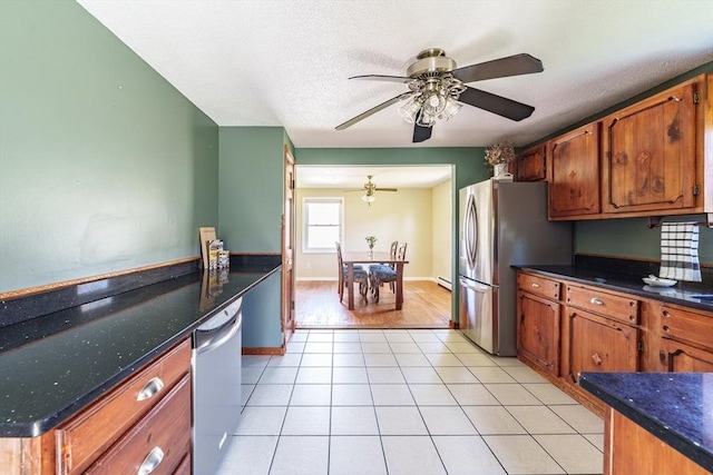 kitchen with light tile patterned flooring, ceiling fan, appliances with stainless steel finishes, and brown cabinetry
