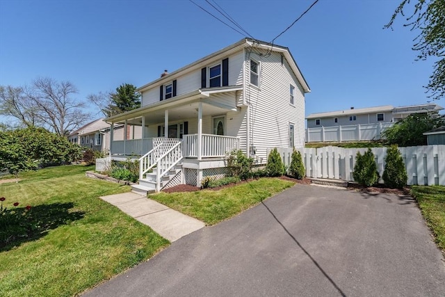 view of front of home with fence, a porch, and a front lawn