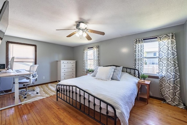 bedroom with baseboards, wood-type flooring, and a textured ceiling