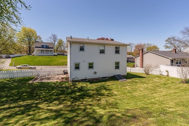 rear view of house featuring a lawn and fence