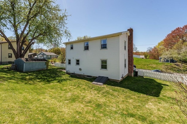 back of house featuring a lawn, fence, central air condition unit, and a chimney