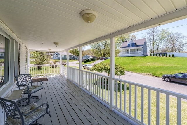 wooden terrace with a porch, a yard, and a residential view