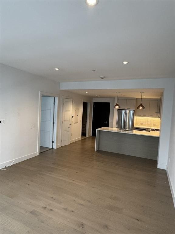 kitchen featuring decorative backsplash, decorative light fixtures, stainless steel refrigerator, and hardwood / wood-style flooring