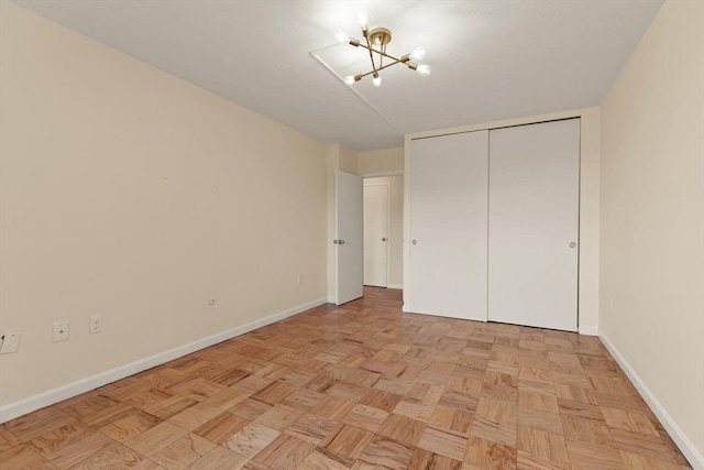 unfurnished bedroom featuring a notable chandelier, a closet, and light parquet flooring