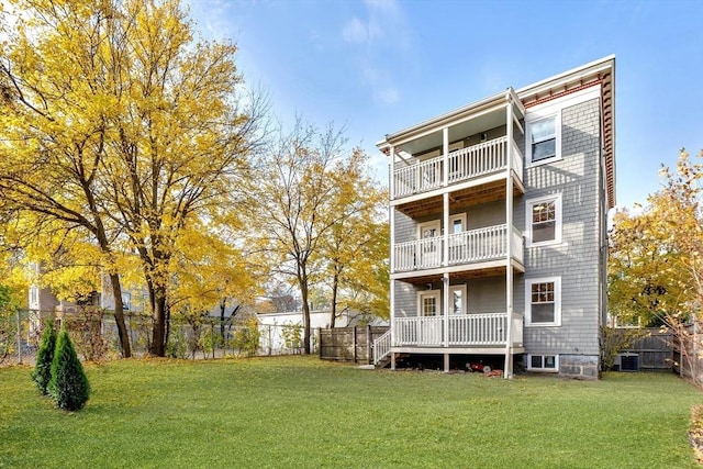 rear view of house with cooling unit, a yard, and a balcony