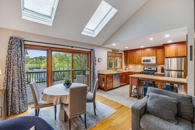 51 Wianno Cir, Barnstable, MA 02655 - dining area featuring a skylight, recessed lighting, high vaulted ceiling, light wood-style floors, and a water view