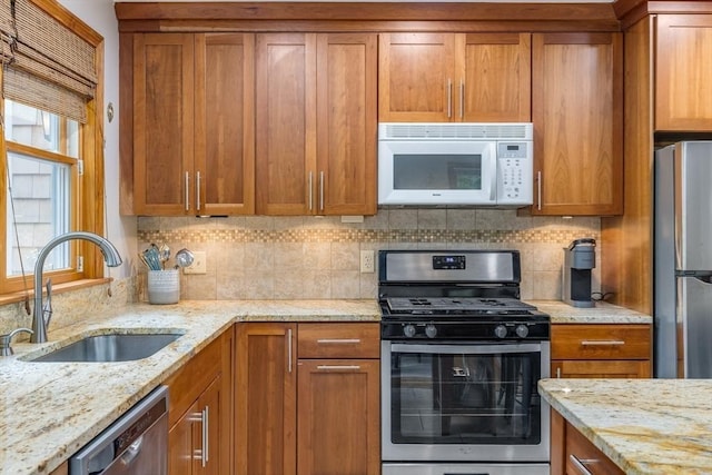 51 Wianno Cir, Barnstable, MA 02655 - kitchen featuring stainless steel appliances, a sink, brown cabinetry, backsplash, and light stone countertops