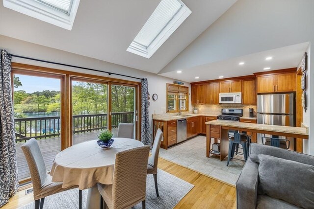 51 Wianno Cir, Barnstable, MA 02655 - dining space featuring a skylight, light wood-style flooring, recessed lighting, high vaulted ceiling, and a water view