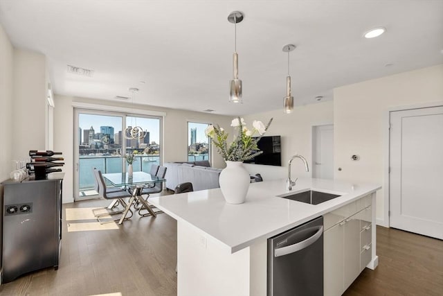 kitchen featuring dark wood-style floors, light countertops, a sink, dishwasher, and hanging light fixtures