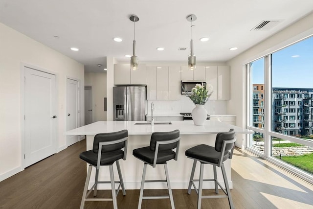 kitchen with dark wood-style flooring, visible vents, a sink, light countertops, and stainless steel appliances