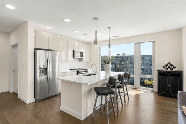 kitchen featuring appliances with stainless steel finishes, a breakfast bar, a sink, and dark wood finished floors