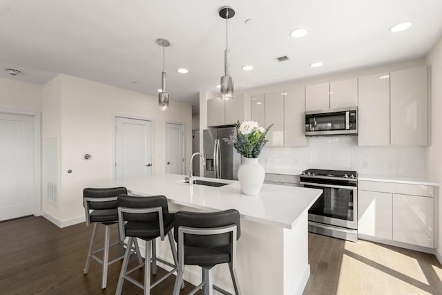 kitchen with appliances with stainless steel finishes, backsplash, dark wood-style flooring, and visible vents
