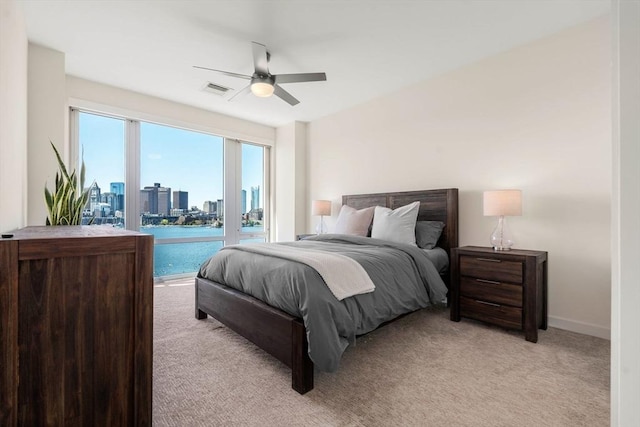 bedroom with visible vents, a ceiling fan, light carpet, access to outside, and a city view