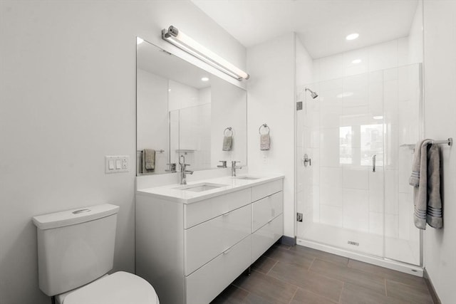 full bathroom featuring double vanity, toilet, a shower stall, and a sink
