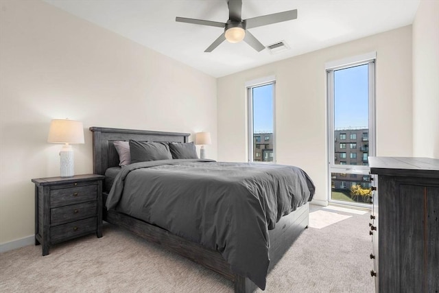 bedroom with ceiling fan, light colored carpet, baseboards, and visible vents