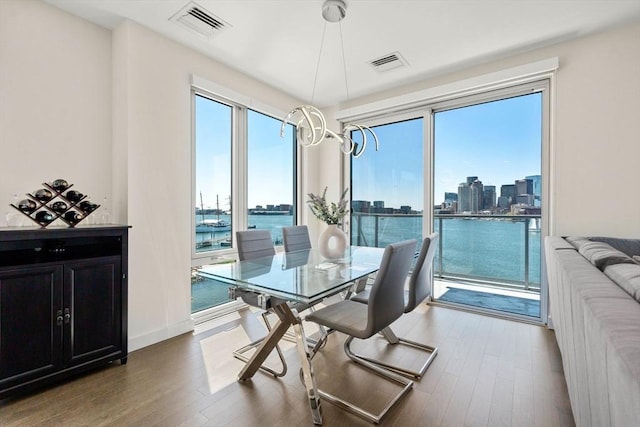 dining area with visible vents, a city view, a water view, and wood finished floors