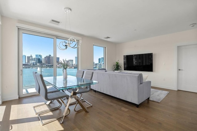dining space featuring an inviting chandelier, baseboards, wood finished floors, and visible vents