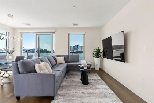 living room with baseboards, plenty of natural light, wood finished floors, and visible vents
