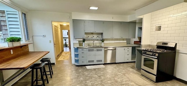 kitchen featuring gray cabinets, sink, stainless steel appliances, and a baseboard heating unit